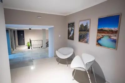 a living room with two chairs and paintings on the wall at Nuevo Centro Hotel Villa Carlos Paz in Villa Carlos Paz