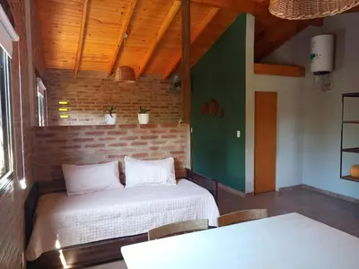 a room with two beds and a table and chairs at La Quina. in Villa Rumipal