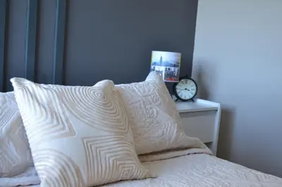 a bed with two pillows and a clock on a table at Departamento Temporario en Alto Villasol in Cordoba