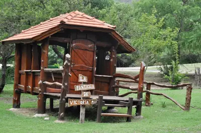 a small wooden hut with a bench in the grass at Cabañas Aufenthalt in Villa General Belgrano