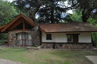 a small house with a tree in front of it at Cabañas Aufenthalt in Villa General Belgrano