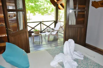 a room with a bed and a balcony with a chair at Cabañas Aufenthalt in Villa General Belgrano