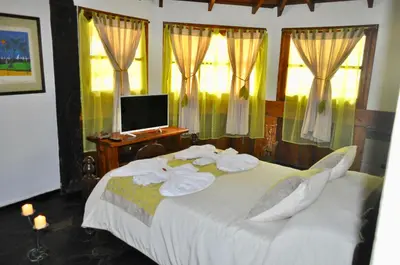 a bedroom with a large white bed with windows at Cabañas Aufenthalt in Villa General Belgrano