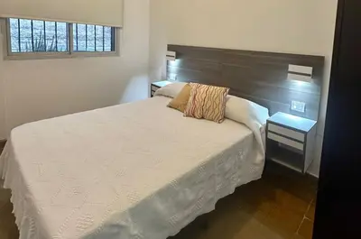 a bedroom with a white bed with a wooden headboard at AMPLIOS Departamentos PASAJE TUCUMÁN in Alta Gracia