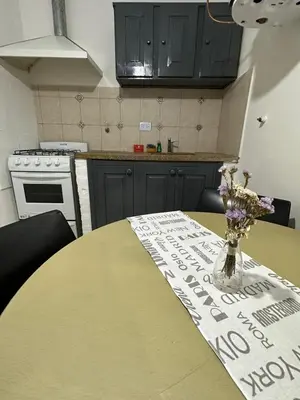 a kitchen with a table with a vase of flowers on it at AMPLIOS Departamentos PASAJE TUCUMÁN in Alta Gracia