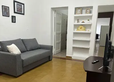 a living room with a gray couch and a television at AMPLIOS Departamentos PASAJE TUCUMÁN in Alta Gracia