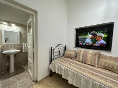 a bathroom with a couch and a tv on the wall at AMPLIOS Departamentos PASAJE TUCUMÁN in Alta Gracia