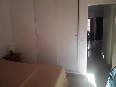 a white bedroom with a bed and a hallway at Departamento de Caroya in Villa Carlos Paz