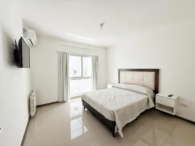 a white bedroom with a bed and a window at VENETO V DEPARTAMENTOS in Villa Carlos Paz