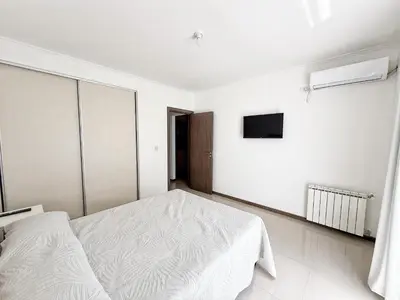 a white bedroom with a bed and a tv at VENETO V DEPARTAMENTOS in Villa Carlos Paz