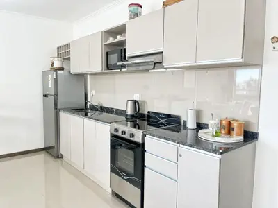a kitchen with white cabinets and a stove top oven at VENETO V DEPARTAMENTOS in Villa Carlos Paz