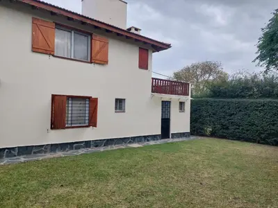a white house with a balcony and a yard at La Casita - Chalet de Montaña in Villa General Belgrano