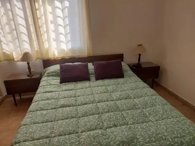 a bedroom with a bed with a green comforter and a window at La Casita - Chalet de Montaña in Villa General Belgrano