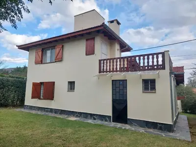 a white house with a balcony on top of it at La Casita - Chalet de Montaña in Villa General Belgrano