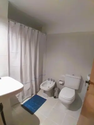 a white bathroom with a toilet and a sink at Güemes apartamento in Cordoba