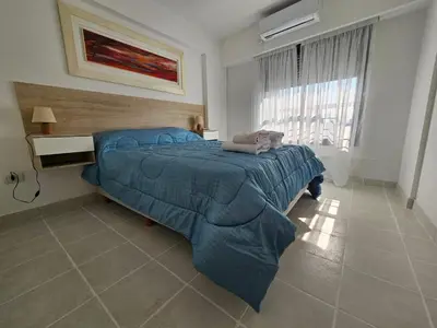 a bedroom with a bed with a blue comforter and a window at Güemes apartamento in Cordoba