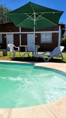 a table and chairs and an umbrella next to a pool at La Algarroba in Alta Gracia
