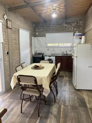 a kitchen with a table and chairs and a refrigerator at cabaña Palmira in Santa Rosa de Calamuchita