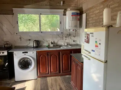 a kitchen with a refrigerator and a washing machine at cabaña Palmira in Santa Rosa de Calamuchita