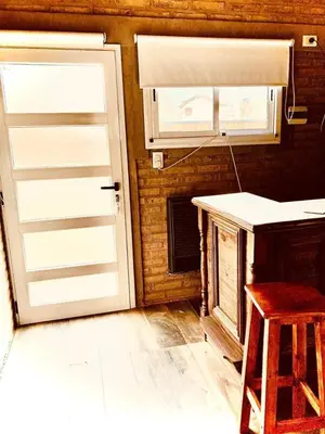 a kitchen with a white door and a table and stool at cabaña Palmira in Santa Rosa de Calamuchita