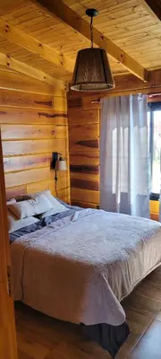 a bedroom with a bed in a wooden cabin at Cabaña los ciruelos in Santa Rosa de Calamuchita