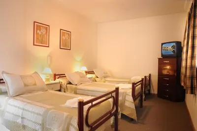 a hotel room with three beds and a tv at Hotel Salerno in Villa Carlos Paz