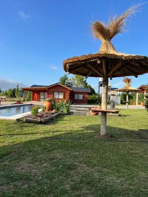 a large straw umbrella in a yard next to a house at Rancho la alborada in Los Reartes