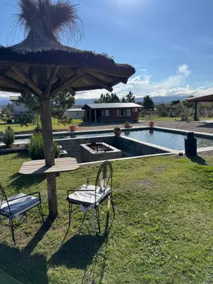 a table and chairs under a umbrella next to a pool at Rancho la alborada in Los Reartes