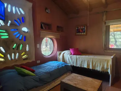 a room with two beds and a table and windows at Alma de Adobe in Merlo