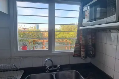 a kitchen with a sink and a microwave and two windows at Alquiler Temporario Zona Céntrica En Córdoba in Cordoba
