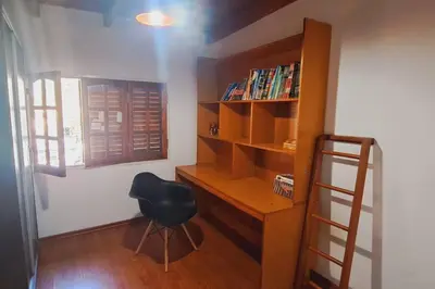 a desk and a chair in a room with a book shelf at Alquiler Temporario Zona Céntrica En Córdoba in Cordoba