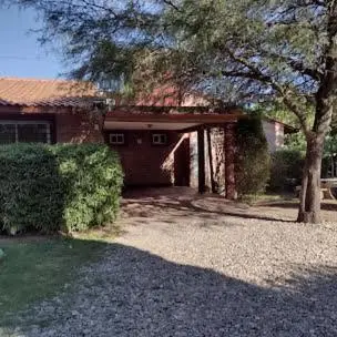 a brick house with a tree and a driveway at Cabañas casanostra in Merlo
