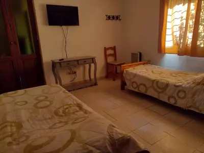 a room with two beds and a table and a tv at Cabañas casanostra in Merlo