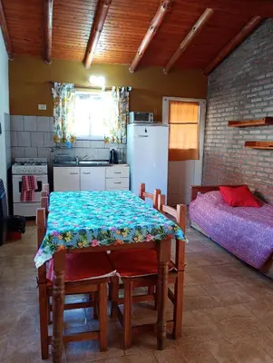 a kitchen with a table and a bed in a room at Cabañas casanostra in Merlo