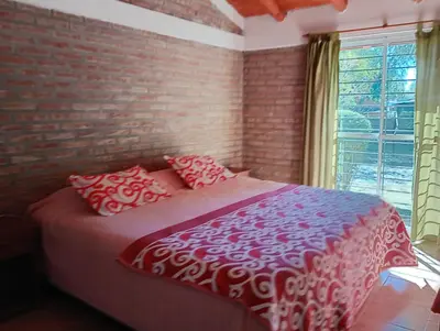 a bedroom with a red and white bed with a brick wall at Cabañas casanostra in Merlo