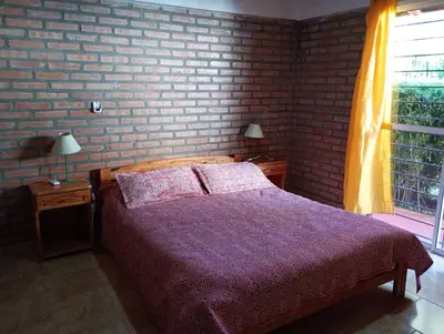 a bedroom with a bed and a brick wall at Cabañas casanostra in Merlo