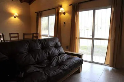 a leather couch in a living room with a large window at Cabanias El Aguaribay in San Javier