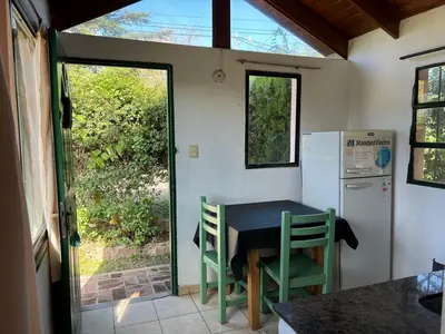 a small kitchen with a table and a refrigerator at Cabañas Los Cedros in Tanti