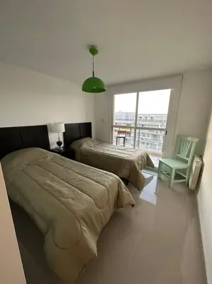 a bedroom with two beds and a chair and a window at Dpto en fontanas del sur, excelentes amenities y muy tranquilo in Cordoba
