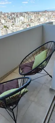 a chair on a balcony with a view of a city at Departamento con seguridad 24hs, gym y pileta! in Cordoba