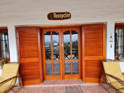 a restaurant with two chairs in front of a door at Cabanas Las Pencas, HOSTERIA in Mina Clavero