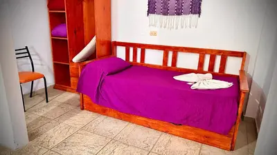 a wooden bed with a purple blanket on it at Cabanas Las Pencas, HOSTERIA in Mina Clavero