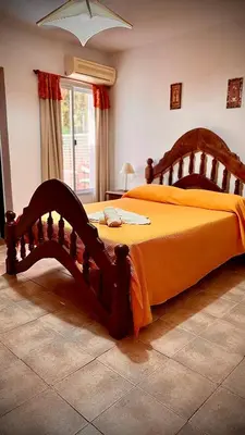 a bedroom with a large bed with an orange bedspread at Cabanas Las Pencas, HOSTERIA in Mina Clavero