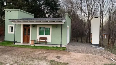 a small green house with a bench in front of it at La Casita in Los Reartes