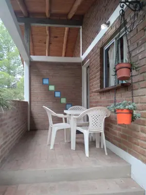 a patio with two chairs and a table on a brick wall at Un lugar en el mundo in Mina Clavero