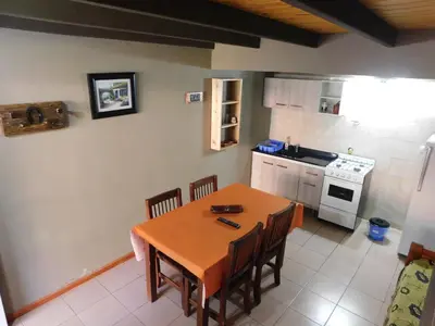 a kitchen with a wooden table with chairs and a stove at Un lugar en el mundo in Mina Clavero