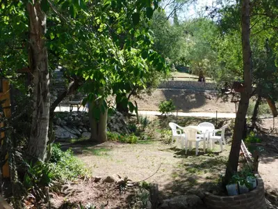 a table and chairs in the shade of trees at Un lugar en el mundo in Mina Clavero
