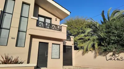 a house with a black door and a balcony at Lacus. Casas de lago. in Almafuerte
