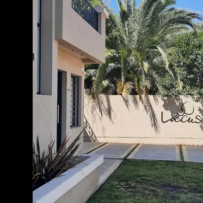 a building with a palm tree next to a fence at Lacus. Casas de lago. in Almafuerte