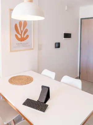 a laptop sitting on a white table with chairs at Departamentos General Paz by Lugar in Cordoba